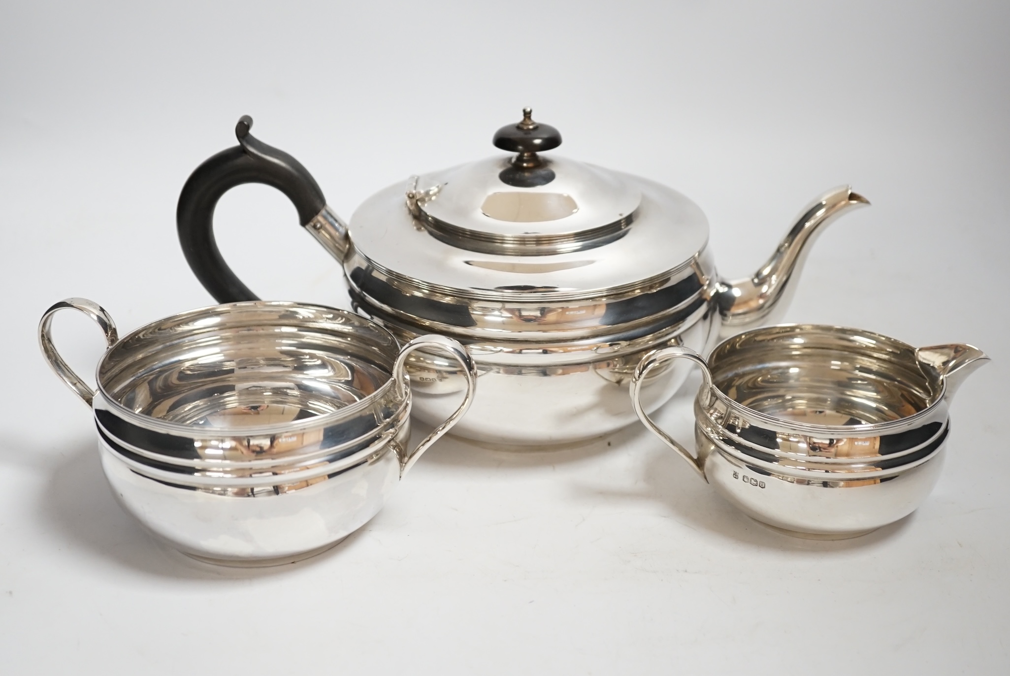 A George V silver three piece circular tea set, with banded girdle, Cooper Brothers & Sons, Sheffield, 1931, 26oz.